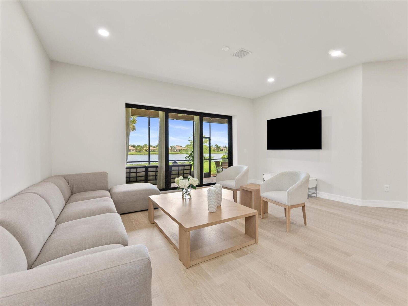 A living room features a light gray sectional sofa, wooden coffee table, and sliding glass doors — 4452 Siena Circle, Wellington FL 33414, WELLINGTON, FL