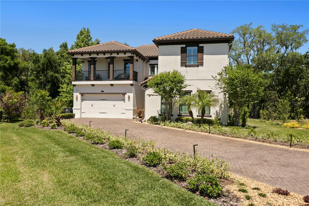 A two-story stucco house with a tiled roof, balcony, and a paved driveway — 7865 MARSH POINTE DRIVE, TAMPA, FL