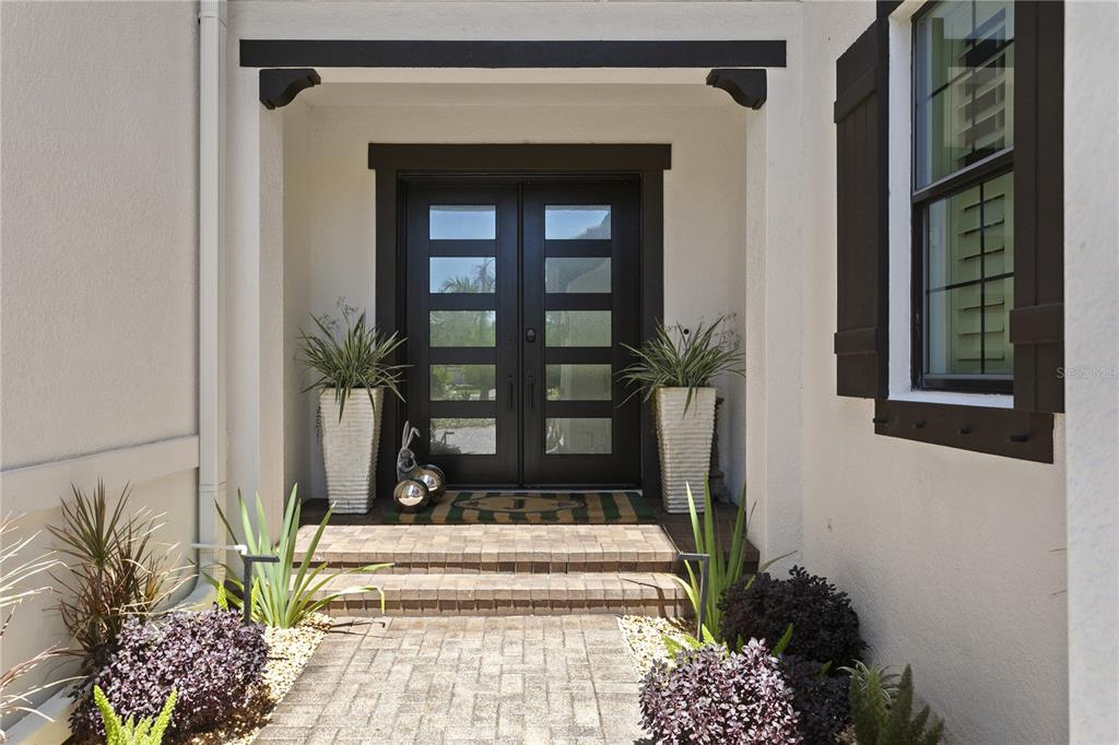 A front entryway features a double door with glass panels, stone steps, and potted plants — 7865 MARSH POINTE DRIVE, TAMPA, FL