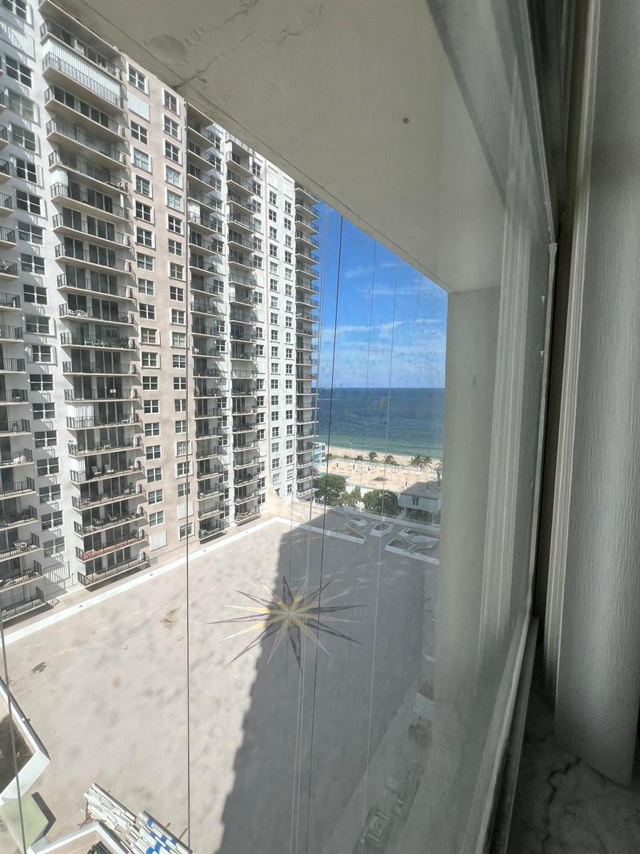 A view from a window overlooking a high-rise building, a courtyard, and the ocean — 111 Briny Avenue # 1511, Pompano Beach FL 33062, POMPANO BEACH, FL