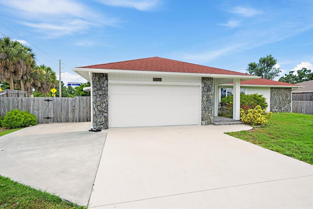 A single-story house with a red roof, stone accents, and a wide concrete driveway — 4378 MEADOWLAND CIRCLE, SARASOTA, FL
