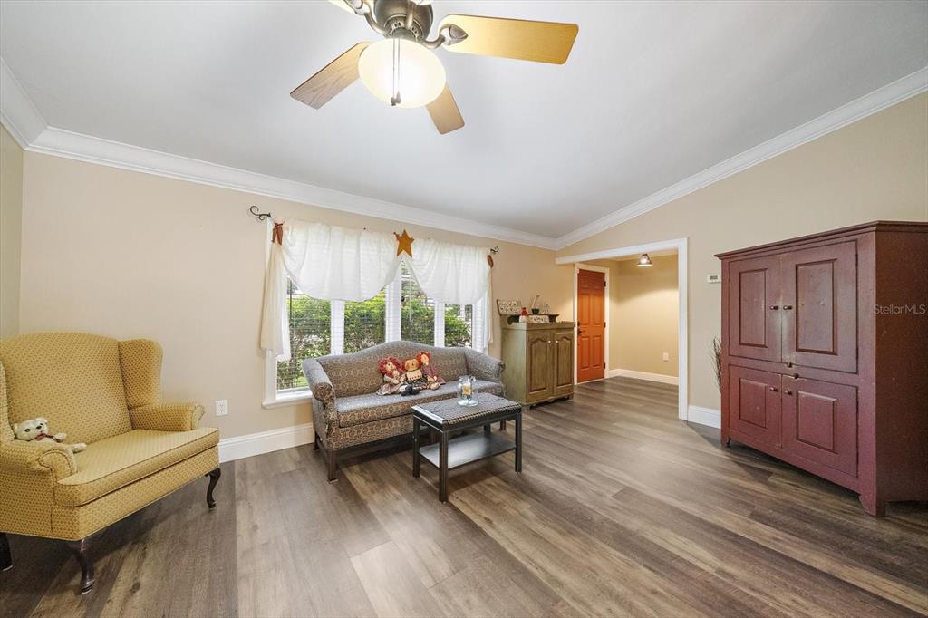 A living room features wood-look flooring, a ceiling fan, a sofa, and a yellow armchair — 4378 MEADOWLAND CIRCLE, SARASOTA, FL