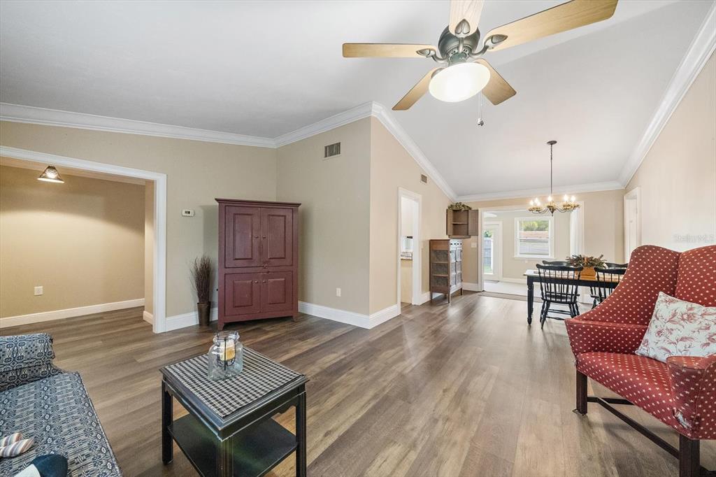A living room with wood-look flooring, a vaulted ceiling, and a dining area beyond — 4378 MEADOWLAND CIRCLE, SARASOTA, FL