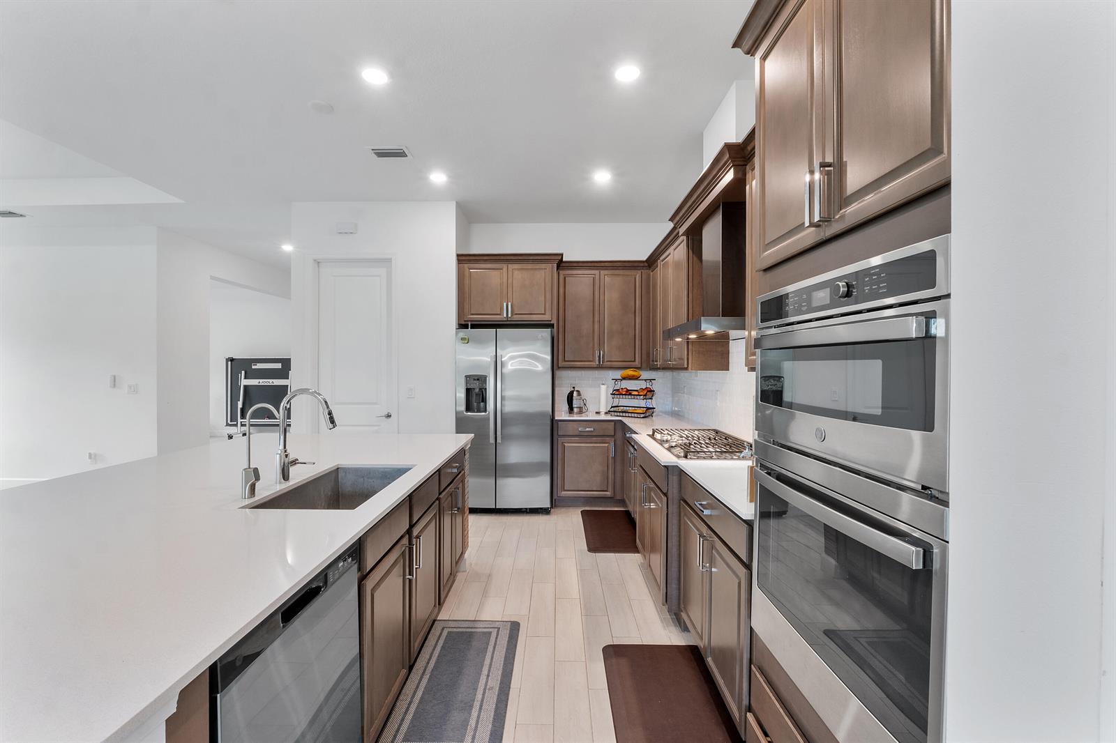 A modern kitchen features dark wood cabinets, stainless steel appliances, and a large white island — 19036 Broad Shore Walk, FL 33470, FL