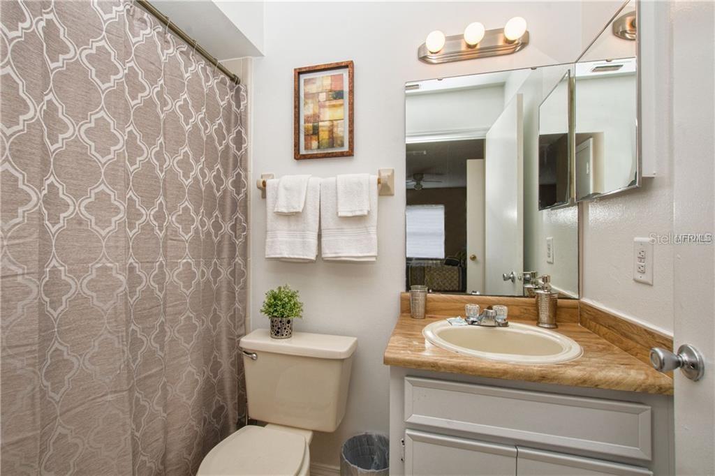 A bathroom features a beige toilet, a vanity with a tan countertop, and a shower curtain — 4160 PERSHING POINTE PLACE UNIT 1, ORLANDO, FL