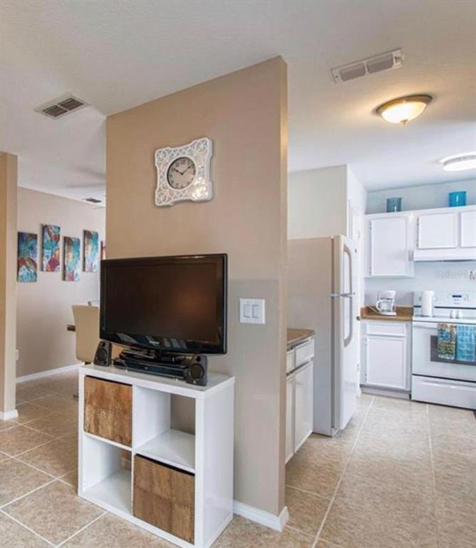 A television sits on a white storage unit in front of a kitchen and dining area — 4160 PERSHING POINTE PLACE UNIT 1, ORLANDO, FL