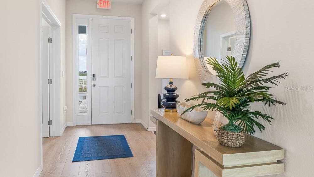 A bright entryway features light wood flooring, a white front door, and a console table — 11909 KINGSLEY TRAIL, PARRISH, FL
