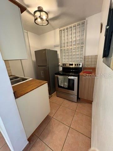 A small kitchen features a stainless steel stove, a refrigerator, and light-colored cabinets — 14 JOSE JULIAN ACOSTA Apt E1, VEGA BAJA, PR