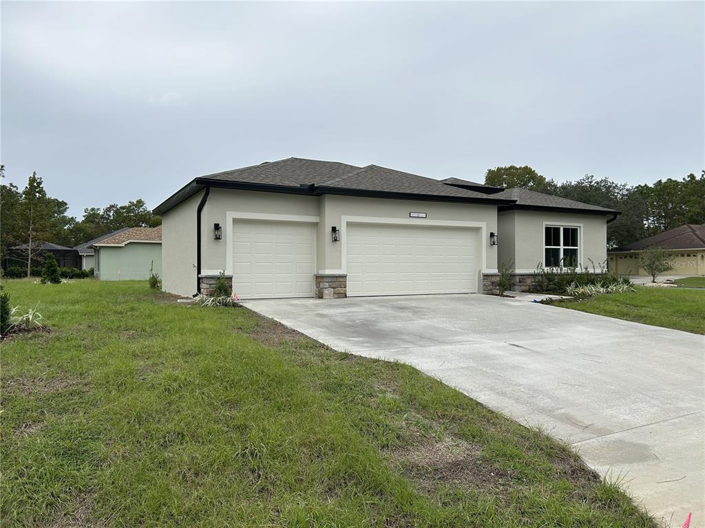 A single-story house with a three-car garage, stone accents, and a concrete driveway — 41 GREENTREE STREET, HOMOSASSA, FL