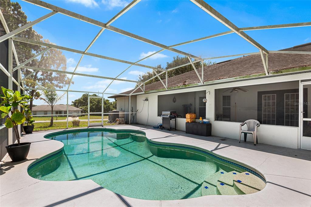 A screened-in patio features a swimming pool with built-in steps and a concrete deck — 2861 POND VIEW DRIVE, HAINES CITY, FL