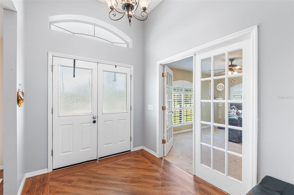 An entryway features wood-look flooring, a double front door, and glass-paned French doors — 2861 POND VIEW DRIVE, HAINES CITY, FL