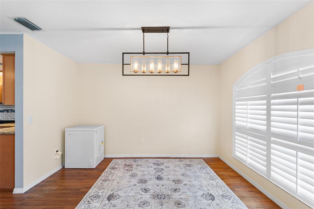 A dining area features a rectangular chandelier, a patterned area rug, and a chest freezer — 2861 POND VIEW DRIVE, HAINES CITY, FL