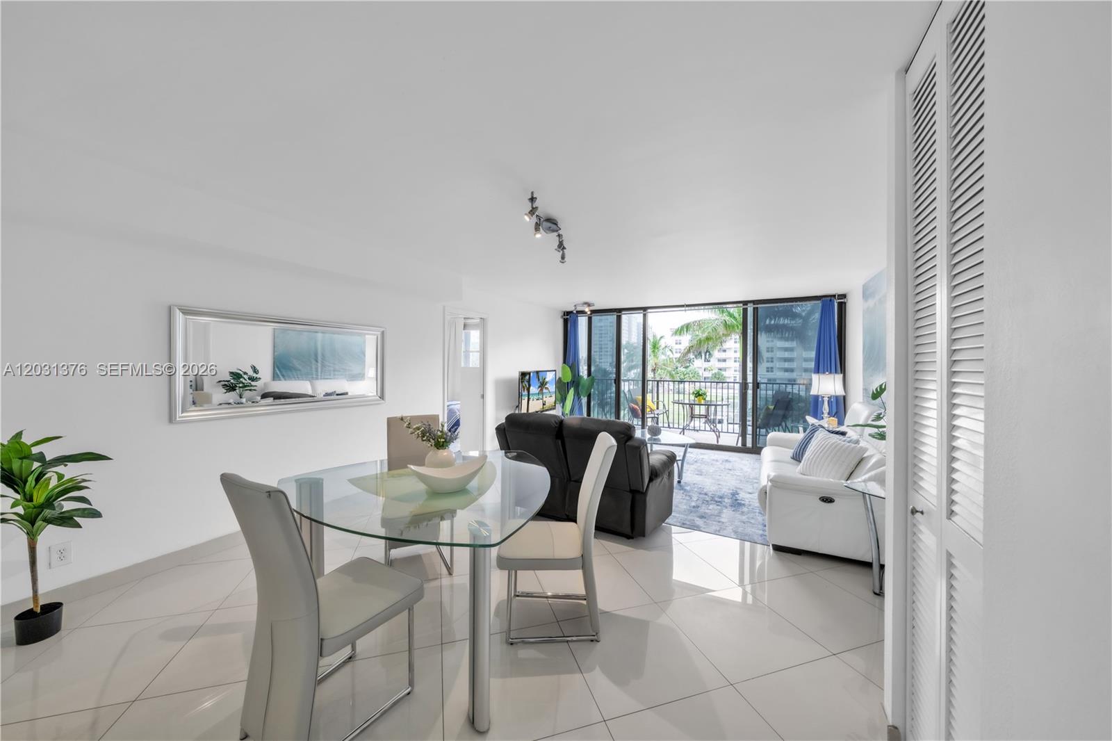 A bright living and dining area features white tile floors, glass furniture, and a balcony — 2101 S Ocean Dr # 204, Hollywood FL 33019, HOLLYWOOD, FL