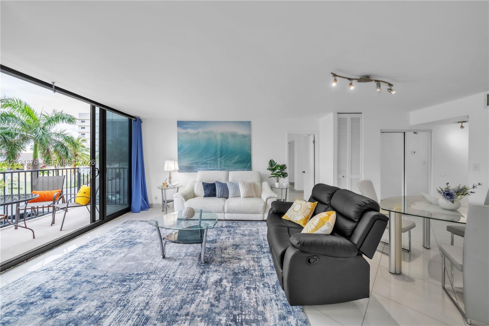 A living room features a white sofa, a black recliner, and a balcony with palm trees — 2101 S Ocean Dr # 204, Hollywood FL 33019, HOLLYWOOD, FL