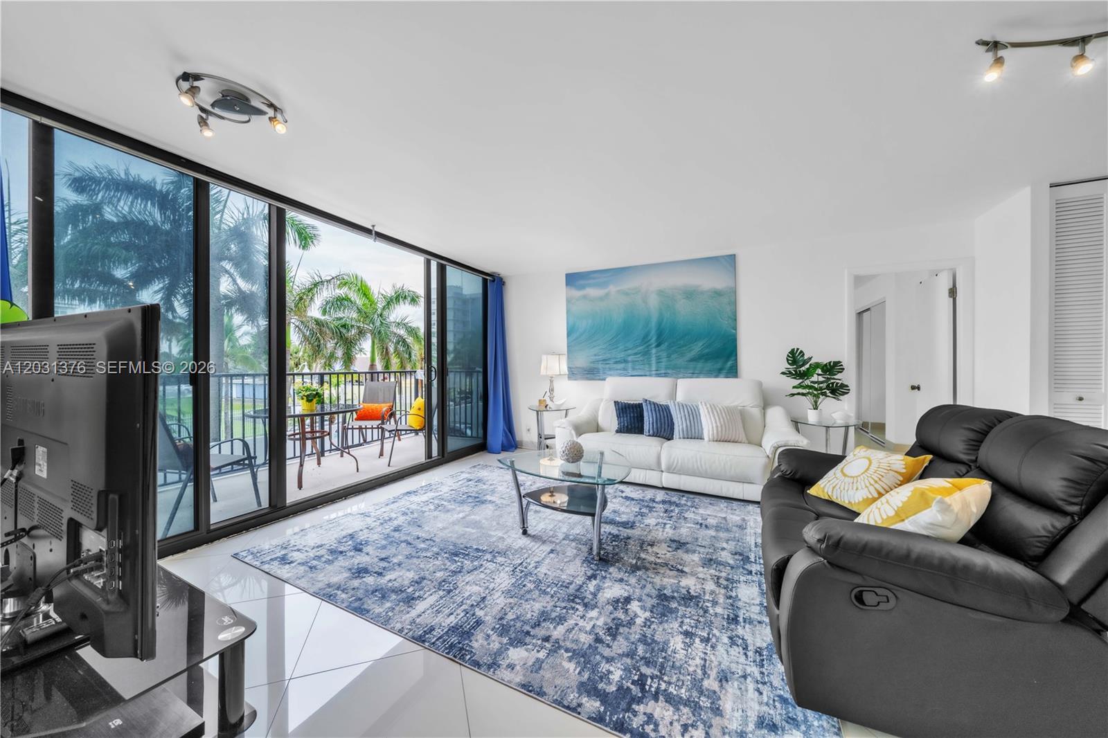 A living room features a white sofa, black recliner, blue area rug, and balcony access — 2101 S Ocean Dr # 204, Hollywood FL 33019, HOLLYWOOD, FL