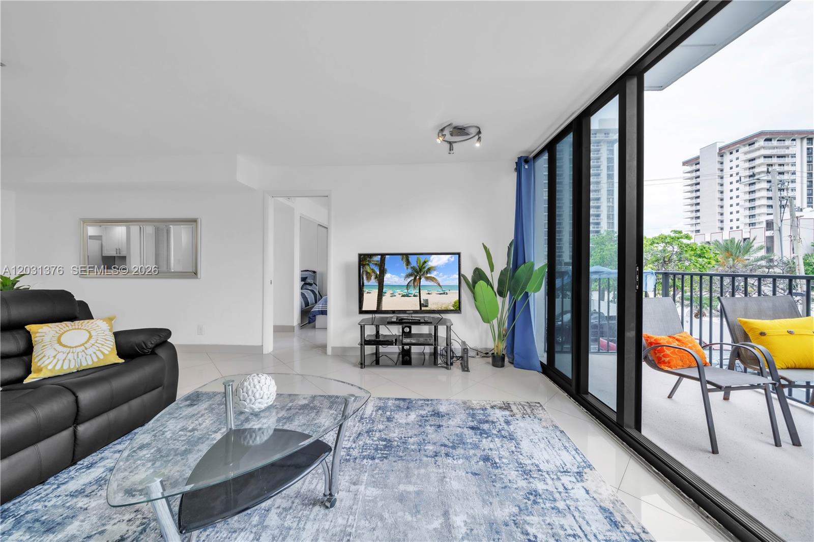 A living room features a black leather sofa, glass coffee table, and balcony access — 2101 S Ocean Dr # 204, Hollywood FL 33019, HOLLYWOOD, FL