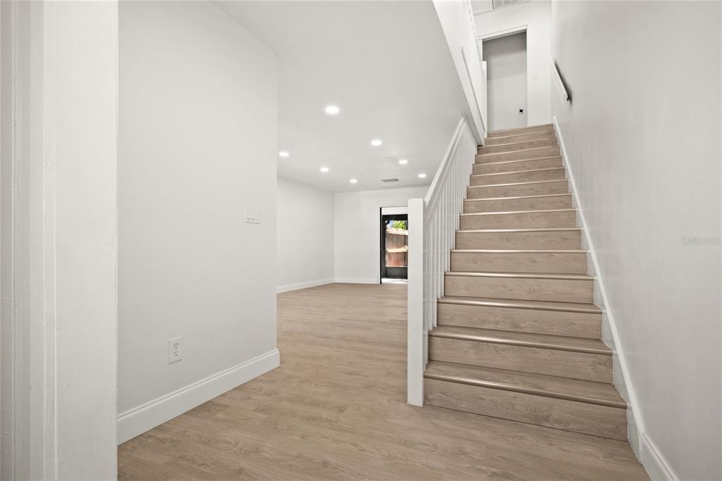 An interior view shows a staircase with light wood steps beside an open living area — 3150 S PINES DRIVE UNIT 84, LARGO, FL