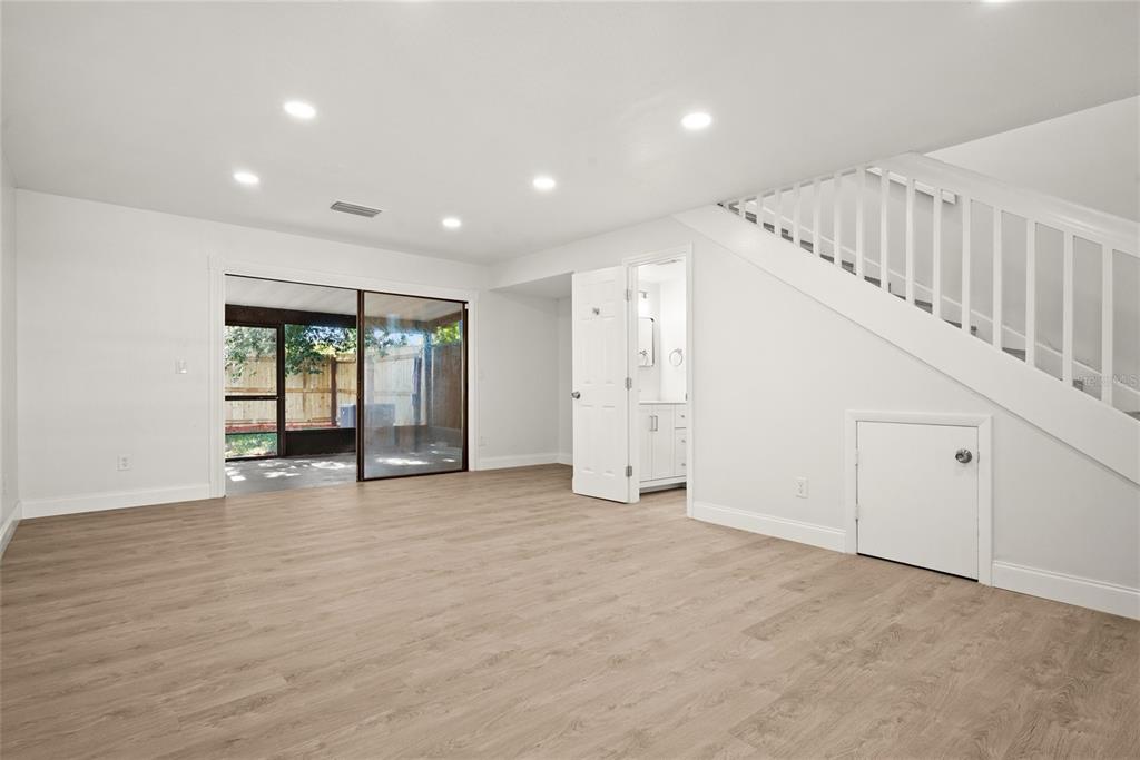 A bright room with light wood-look flooring, a staircase, and a sliding door to a patio — 3150 S PINES DRIVE UNIT 84, LARGO, FL