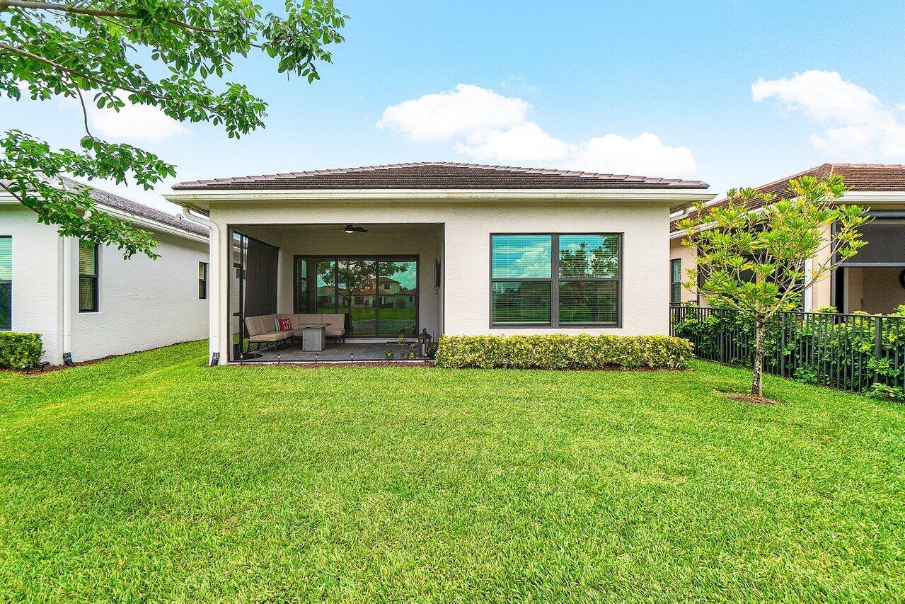 The backyard features a covered patio with a seating area and a large grassy lawn — 16070 Key Biscayne Lane, Westlake FL 33470, WESTLAKE, FL