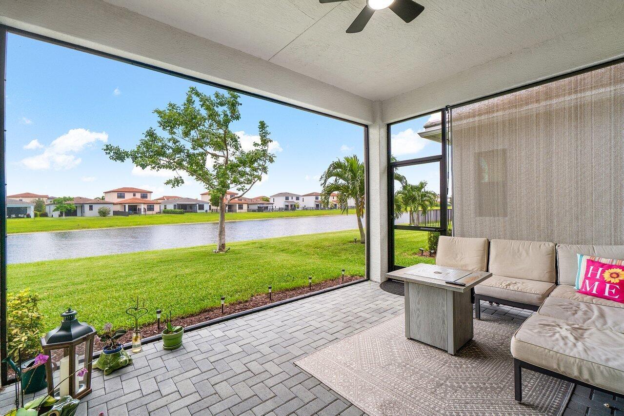 A screened-in patio features a brick floor, outdoor furniture, and a view of a lake — 16070 Key Biscayne Lane, Westlake FL 33470, WESTLAKE, FL