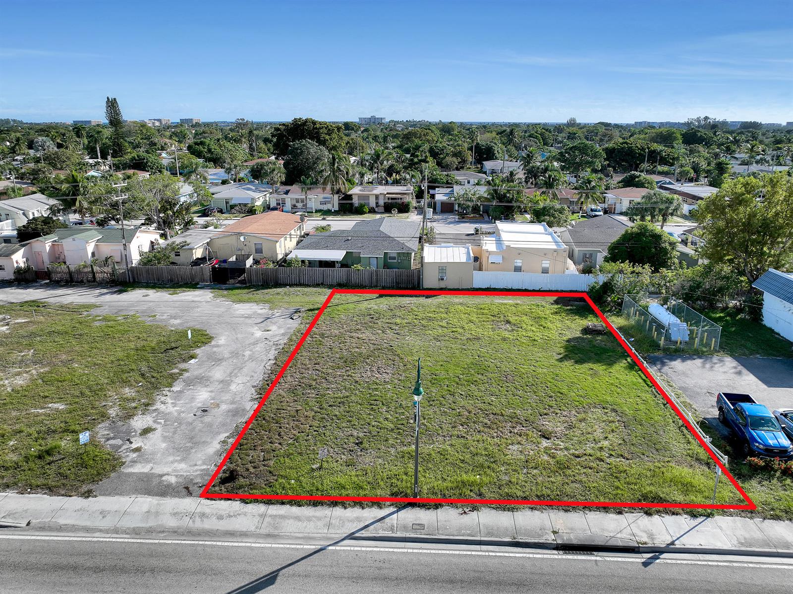 An aerial view shows a rectangular vacant lot outlined in red next to a blue truck — 1616 N Dixie Highway, FL 33460, FL