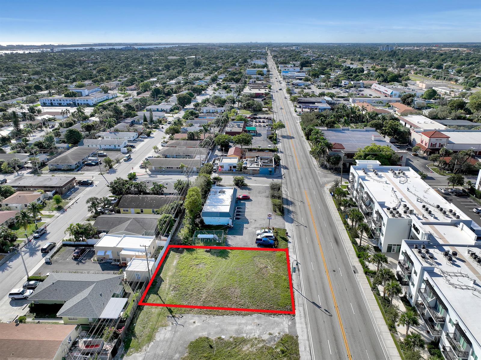 An aerial view shows a vacant, rectangular grass lot outlined in red along a busy road — 1616 N Dixie Highway, FL 33460, FL