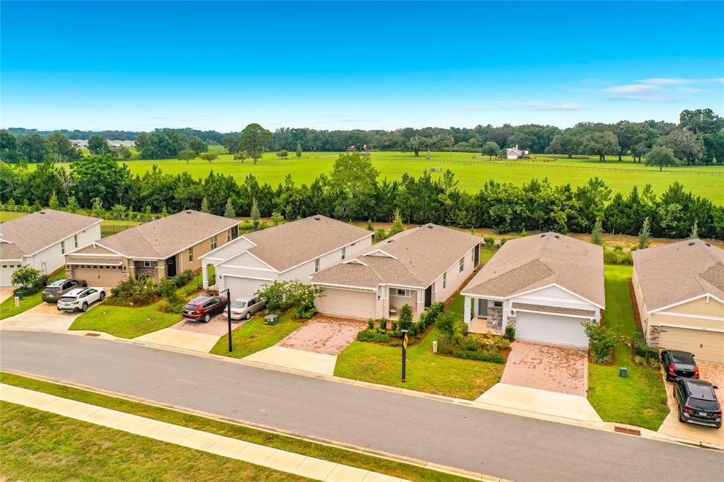 An aerial view shows a row of suburban houses with driveways facing a large green field — 4143 NW 44TH CIRCLE, OCALA, FL