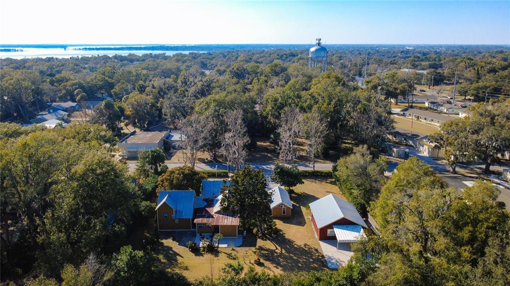 An aerial view shows a house with a metal roof, detached garage, and water tower — 1148 N GRANDVIEW STREET, MOUNT DORA, FL