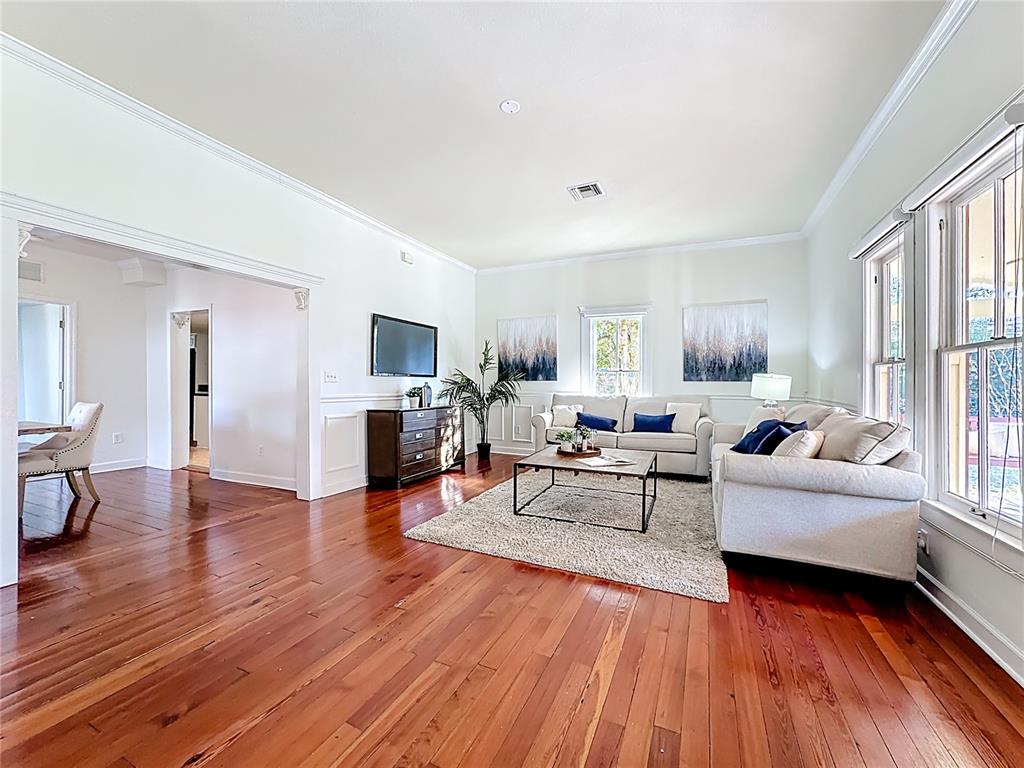 A living room features hardwood floors, white walls, a sofa, and a television — 1148 N GRANDVIEW STREET, MOUNT DORA, FL