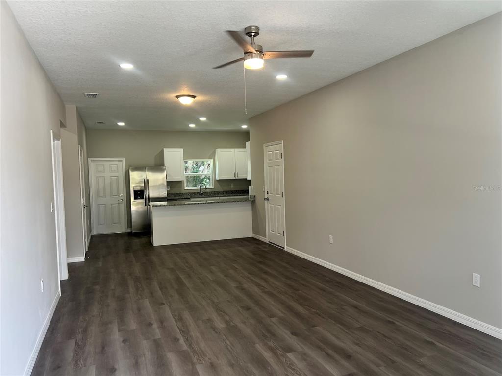 An open-concept kitchen and living area features dark wood-look flooring, gray walls, and white cabinets — 5008 FINDERS COURT, TAMPA, FL