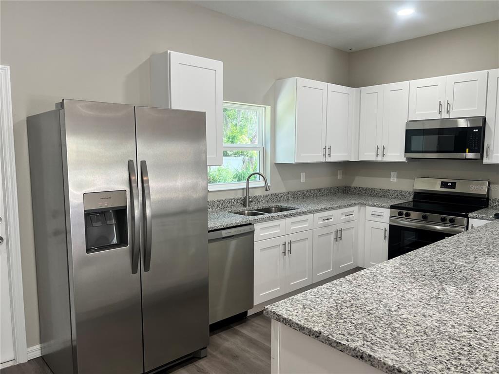 A kitchen features white cabinets, granite countertops, and stainless steel appliances — 5008 FINDERS COURT, TAMPA, FL