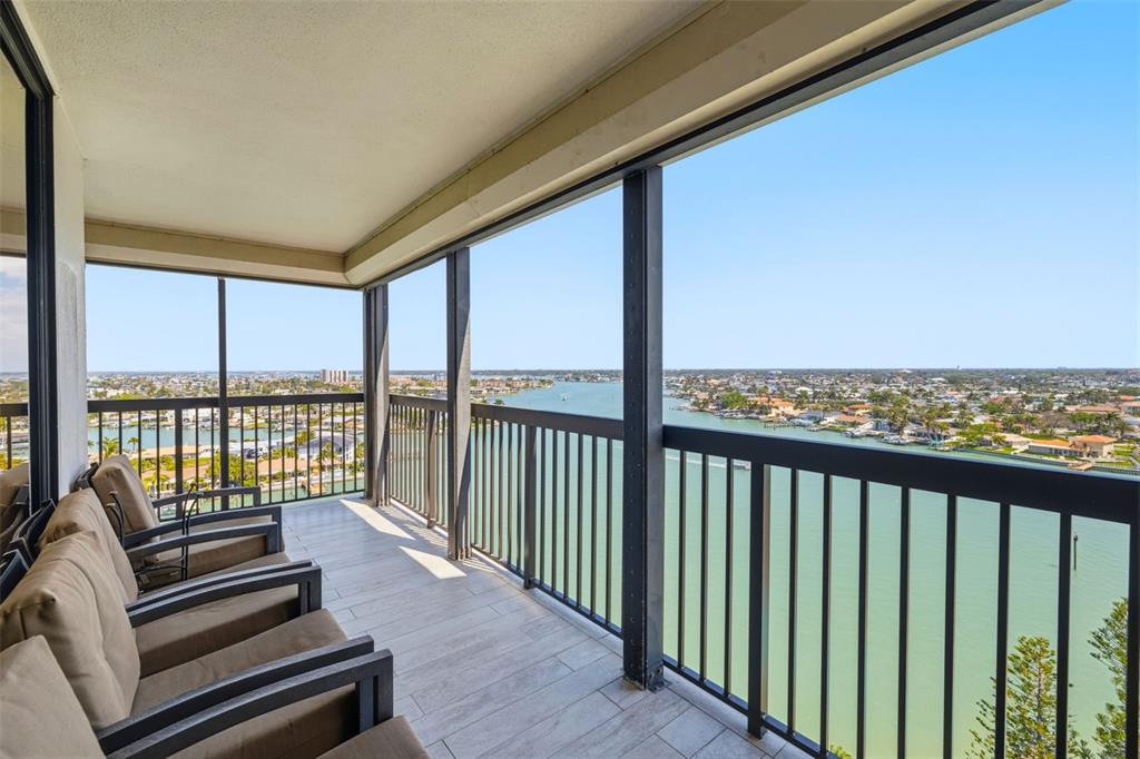 A screened balcony with tiled flooring and outdoor seating overlooking a wide coastal waterway — 9495 BLIND PASS ROAD UNIT 1208, ST PETE BEACH, FL