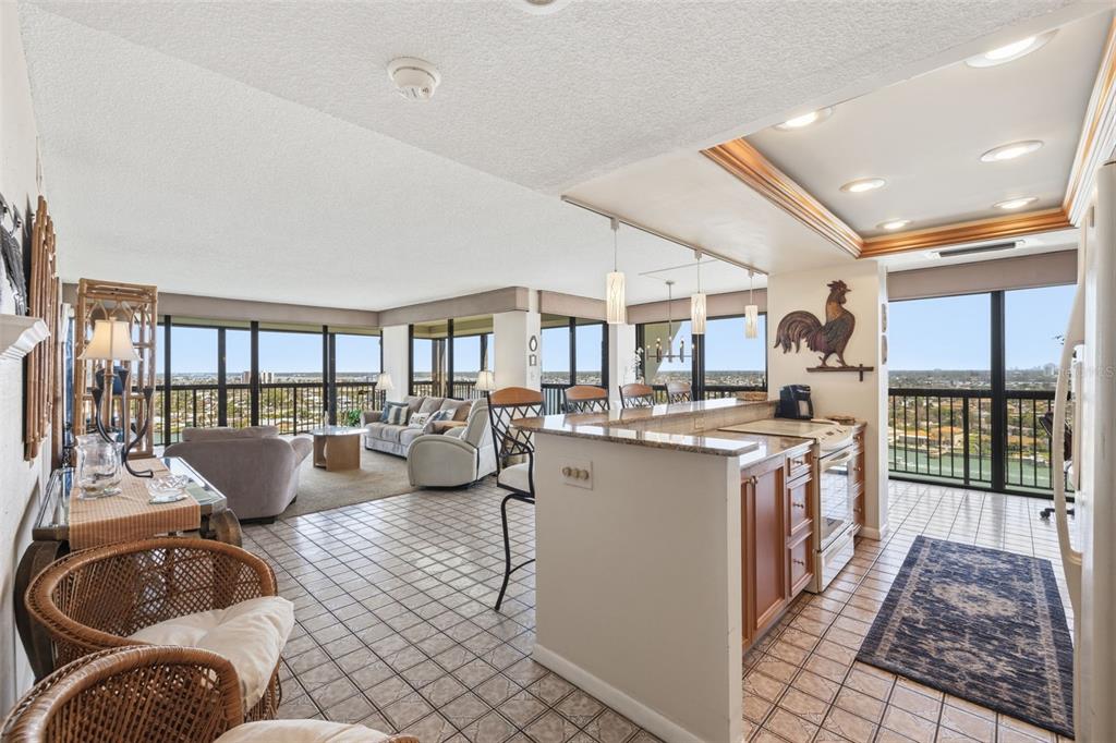 An open-concept kitchen and living area with tile floors, a breakfast bar, and floor-to-ceiling windows — 9495 BLIND PASS ROAD UNIT 1208, ST PETE BEACH, FL