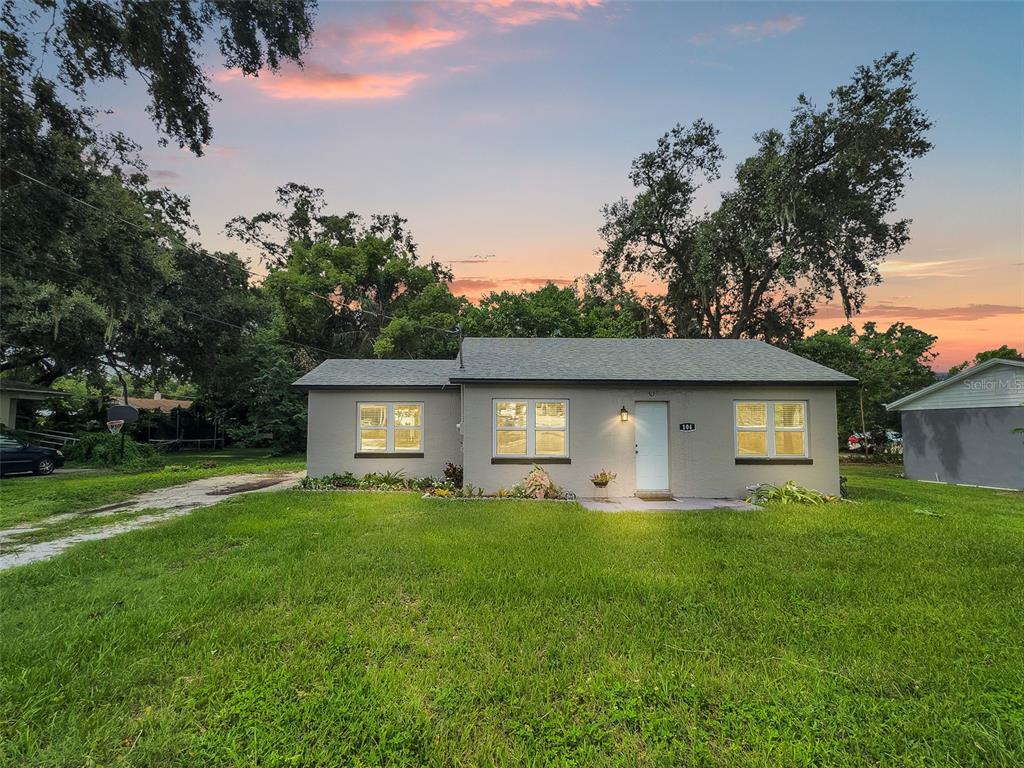 A single-story gray house with a white door and three windows sits on a lawn — 104 AVENUE K NE, WINTER HAVEN, FL