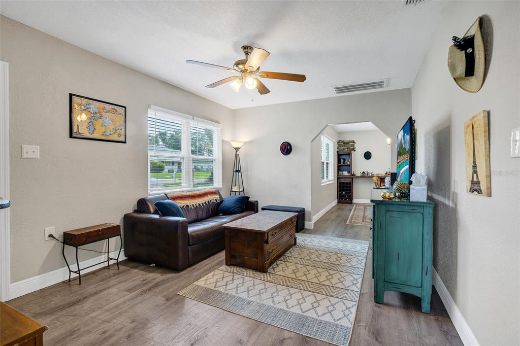 A living room features a brown leather sofa, a patterned rug, and a teal cabinet — 104 AVENUE K NE, WINTER HAVEN, FL