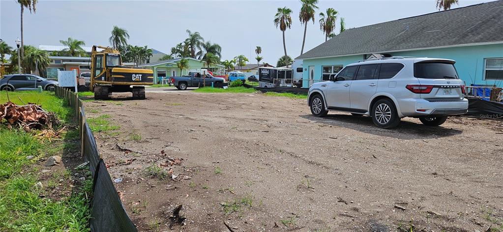 A vacant dirt lot features a yellow excavator and a parked silver SUV — 623 180TH AVENUE E, REDINGTON SHORES, FL