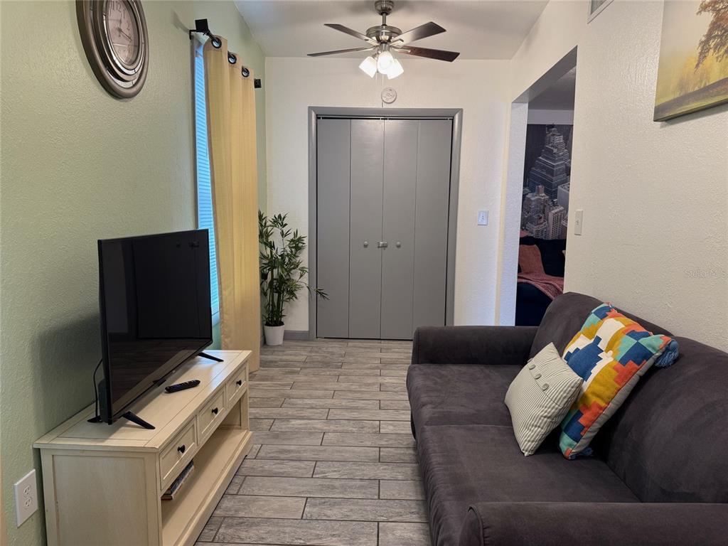 A living room features a gray sofa, a white media console, and a gray closet — 907 N WABASH AVE, LAKELAND, FL