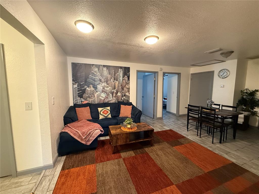 A living room features a blue sofa, a wooden coffee table, and a city skyline mural — 907 N WABASH AVE, LAKELAND, FL