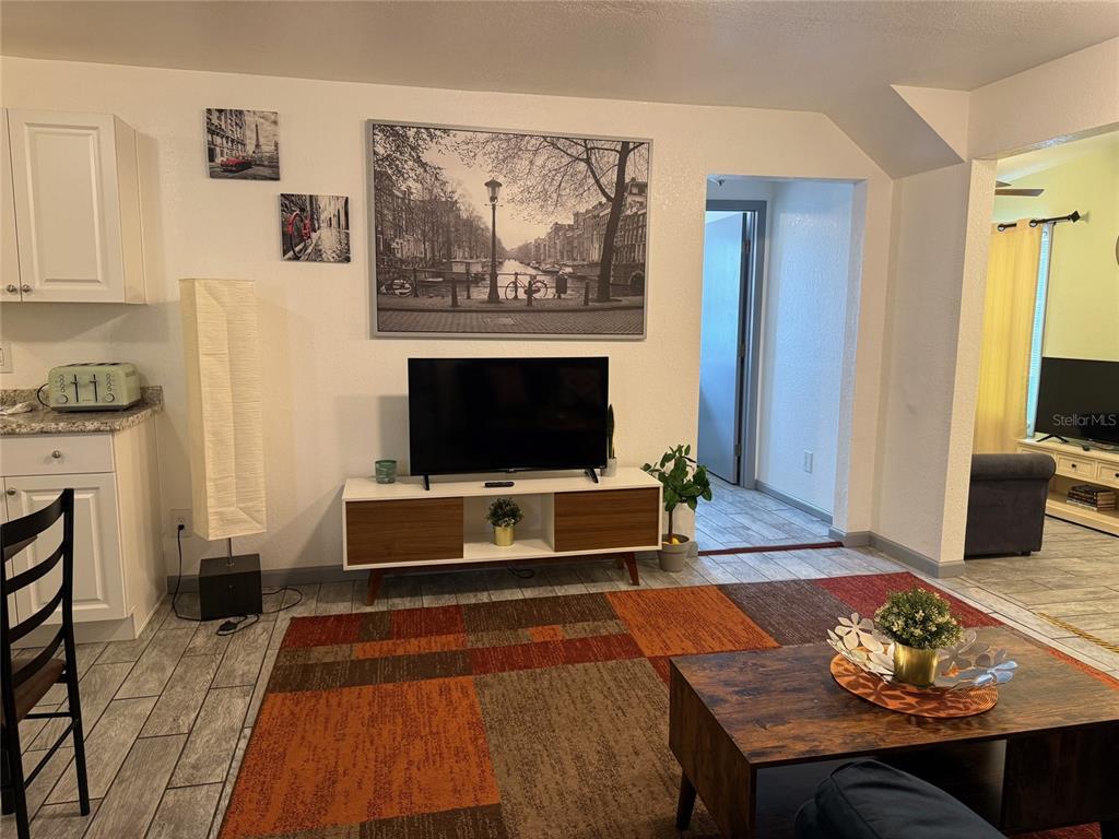 A living room features a television on a media console, a patterned rug, and tile flooring — 907 N WABASH AVE, LAKELAND, FL