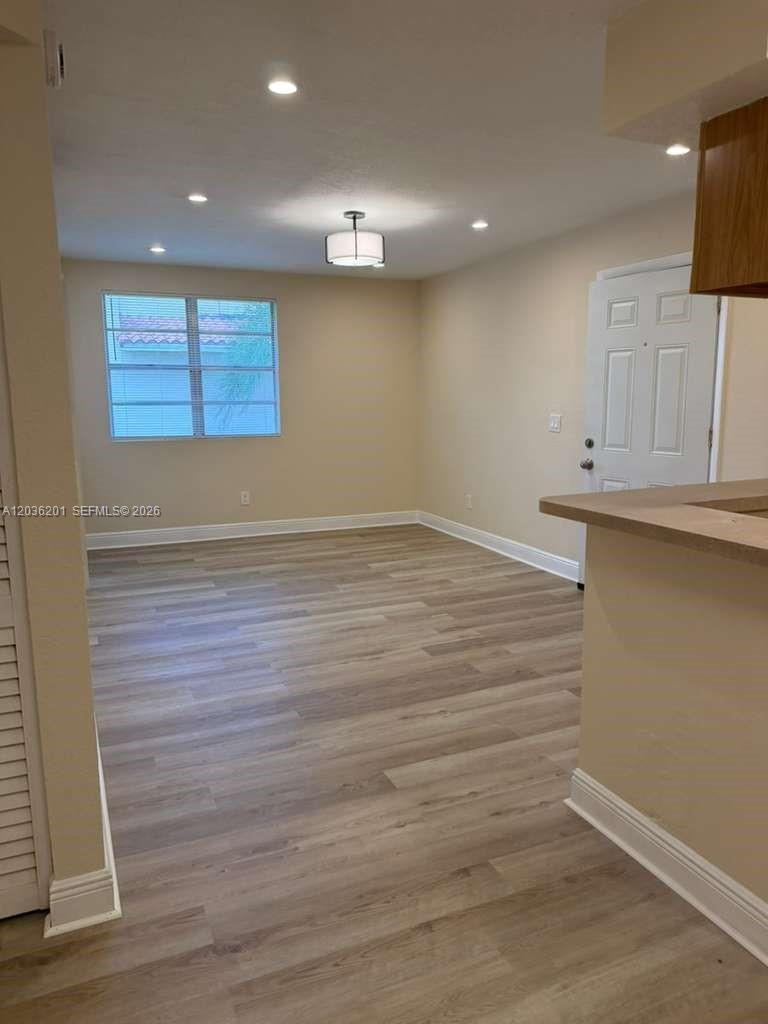 An empty room features light-colored wood-look flooring, a window with blinds, and recessed lighting — 1247 SW 46th Ave # 1306, Pompano Beach FL 33069, POMPANO BEACH, FL