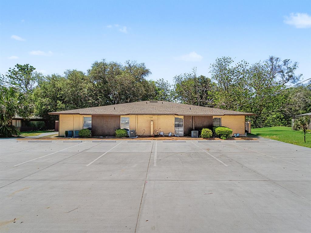 A single-story duplex building with a brown roof sits behind a large concrete parking lot — 2950 SE 53RD COURT, OCALA, FL
