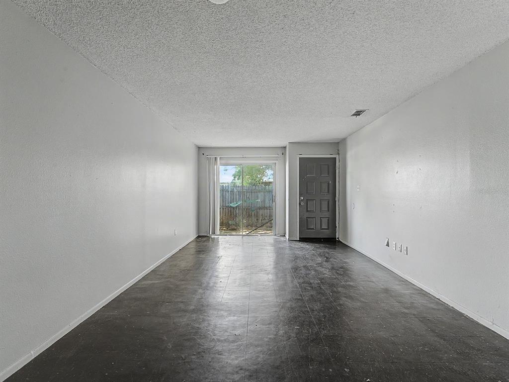 An empty room with white walls, a dark floor, a sliding glass door, and a door — 2950 SE 53RD COURT, OCALA, FL