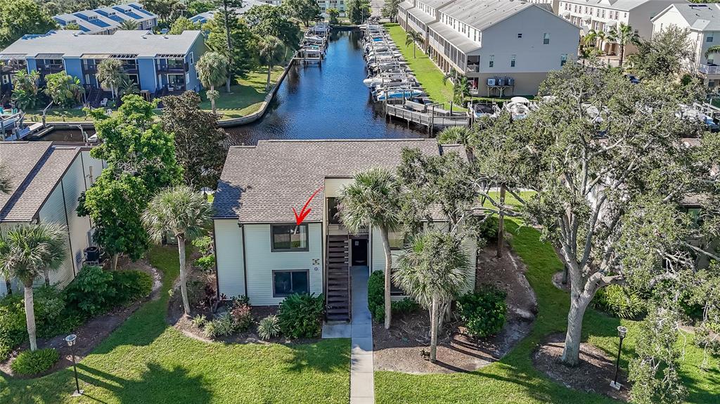 An aerial view shows a two-story residential building with a red arrow pointing to a window — 372 MOORINGS COVE DRIVE UNIT 372, TARPON SPRINGS, FL