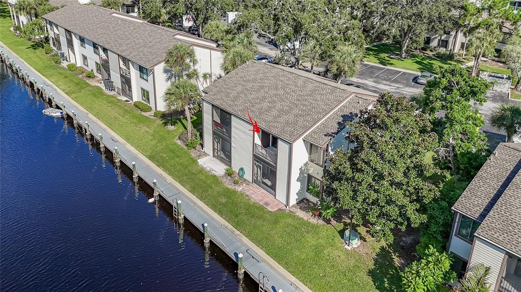 An aerial view of a multi-story apartment building situated along a canal with a dock — 372 MOORINGS COVE DRIVE UNIT 372, TARPON SPRINGS, FL