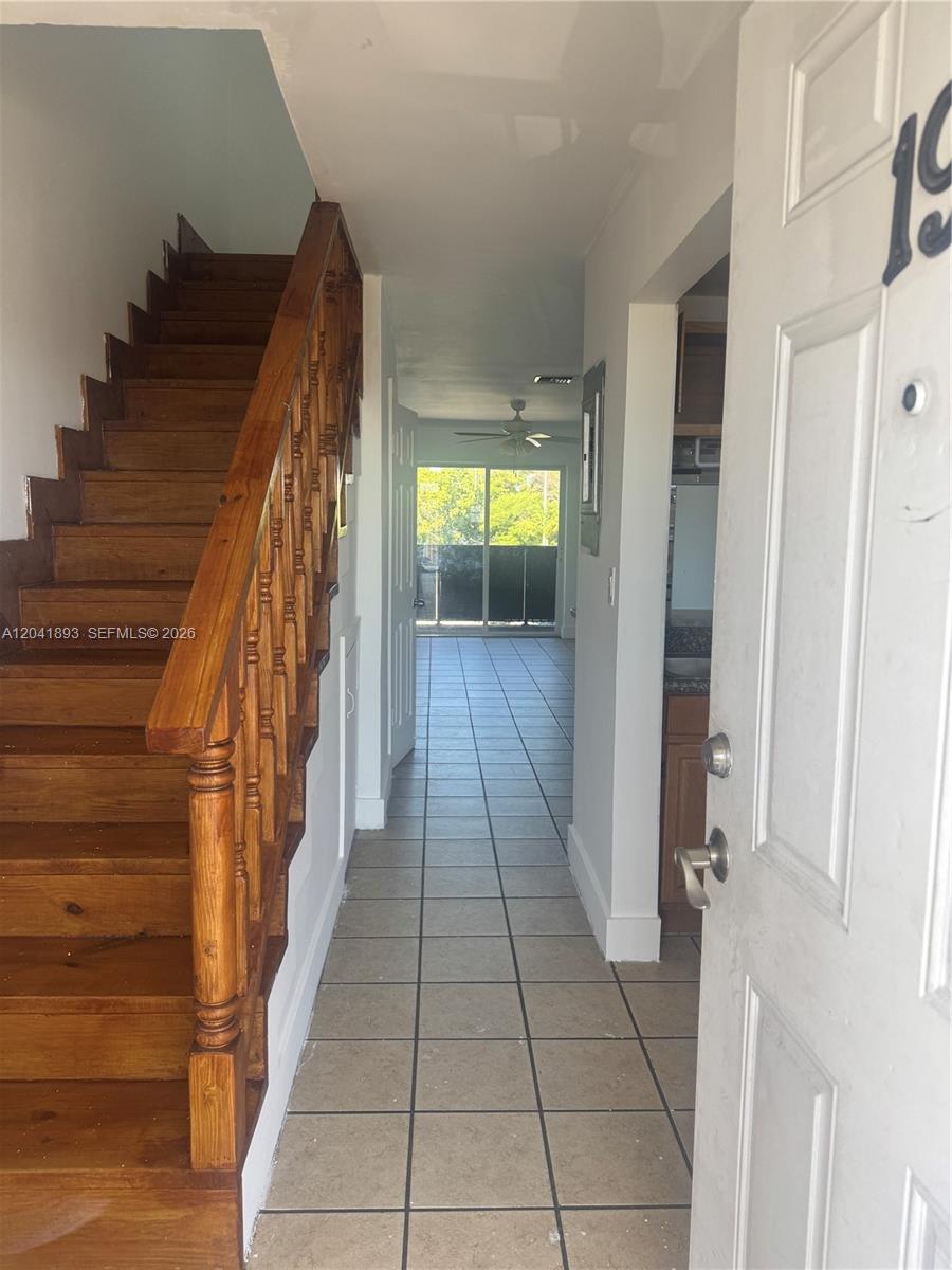 An entryway features a wooden staircase on the left and a tiled hallway leading outside — 1551 W Okeechobee Rd # 19, Hialeah FL 33010, HIALEAH, FL