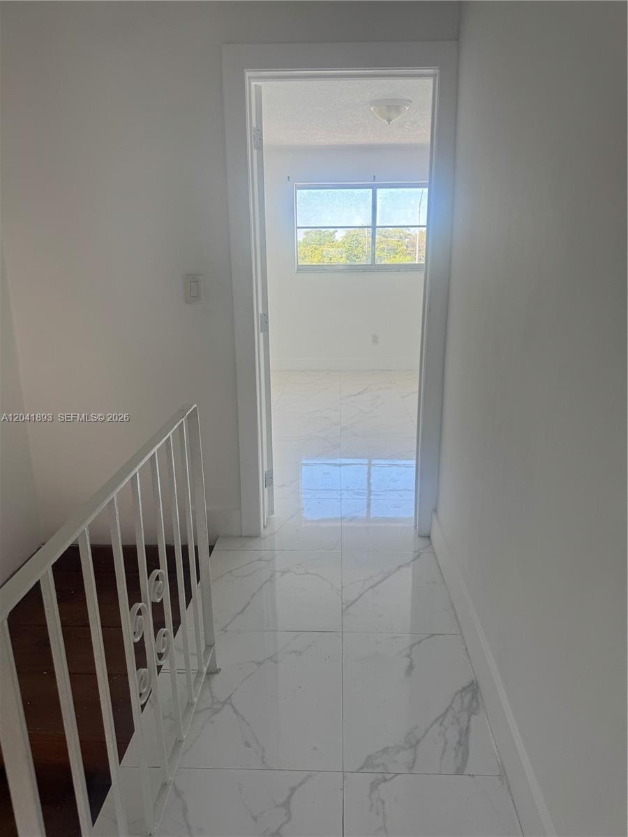 A hallway with white marble-look tile flooring leads into a bedroom through a doorway — 1551 W Okeechobee Rd # 19, Hialeah FL 33010, HIALEAH, FL