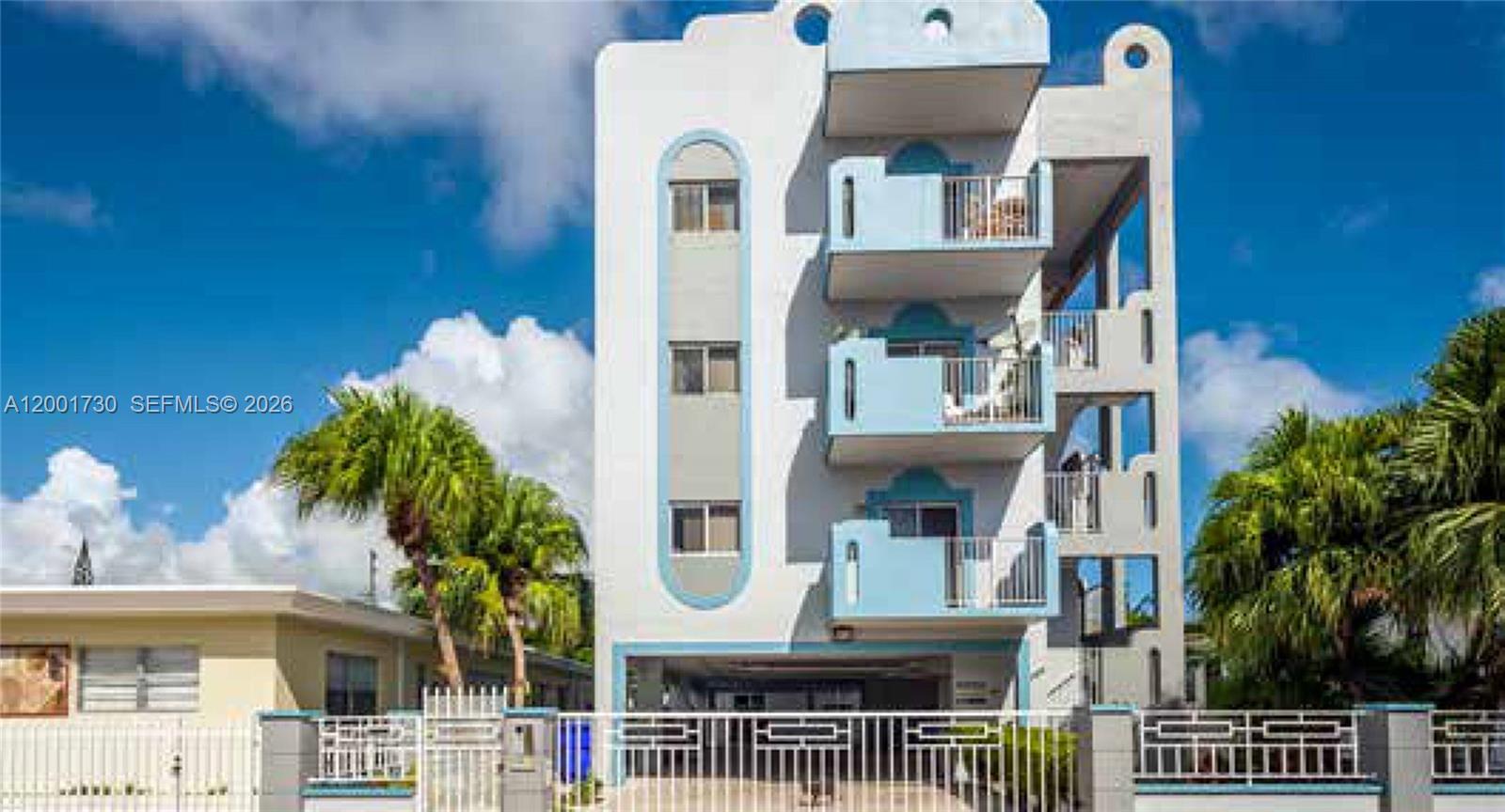 A multi-story apartment building features stacked balconies and a ground-level parking area behind a fence — 709 83rd St, Miami Beach FL 33141, MIAMI BEACH, FL