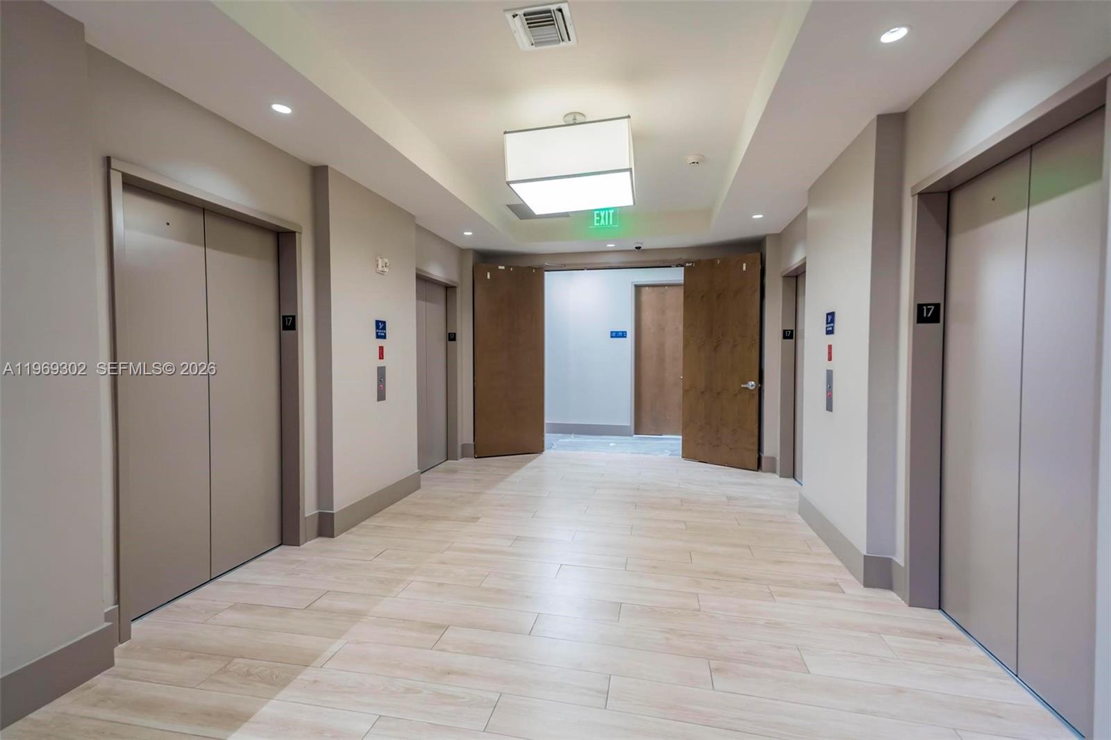 A hallway features light wood-look flooring, multiple elevator doors, and a central exit doorway — 175 SW 7th St # 1715, Miami FL 33130, MIAMI, FL