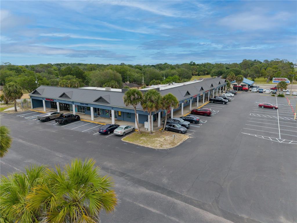 An aerial view shows a single-story commercial strip mall with a parking lot — 9413 SE MARICAMP ROAD, OCALA, FL