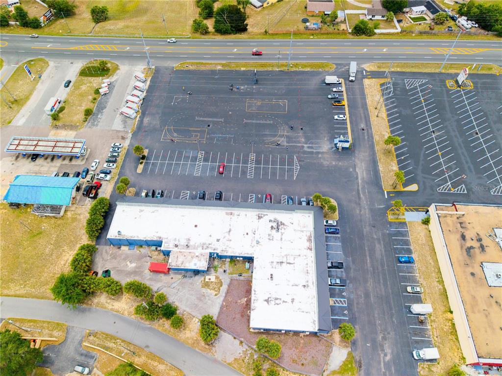 An aerial view shows a commercial building with a large parking lot and adjacent road — 9413 SE MARICAMP ROAD, OCALA, FL